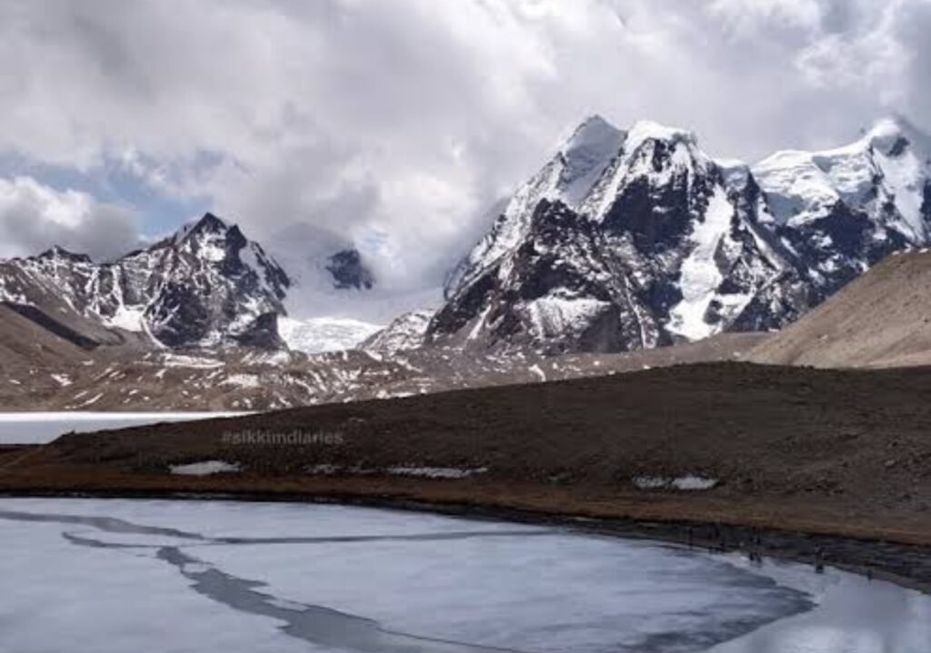 Panoramic view of Gurudongmar Lake surrounded by snowy mountains