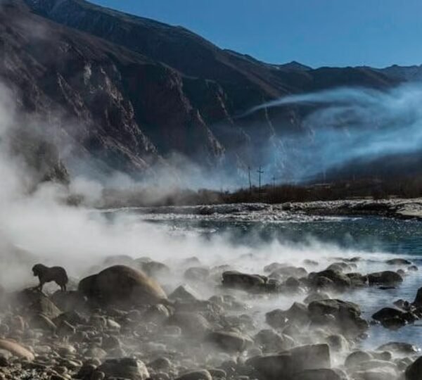 Steam rising from natural hot springs surrounded by snow and rocks